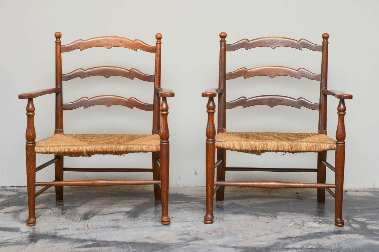 Pair of English provincial diminutive oak low armchairs (fauteuils) with rush seats, circa 1860. Seat Height: 12 in.