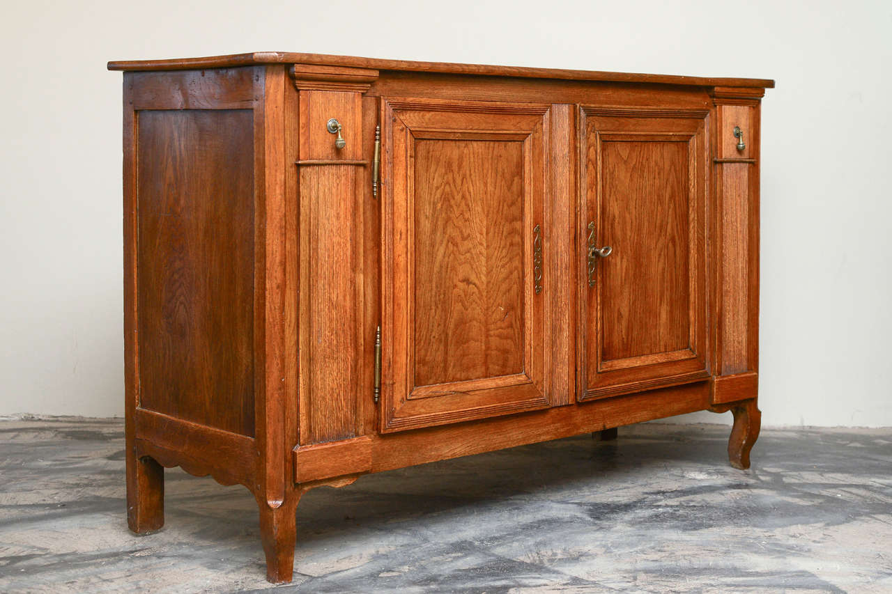 French provincial (transitional Louis XV / XVI style) oak buffet cabinet with stylized neo-classical reeded pilasters with drawers over carved feet, two removable doors, circa 1850.
