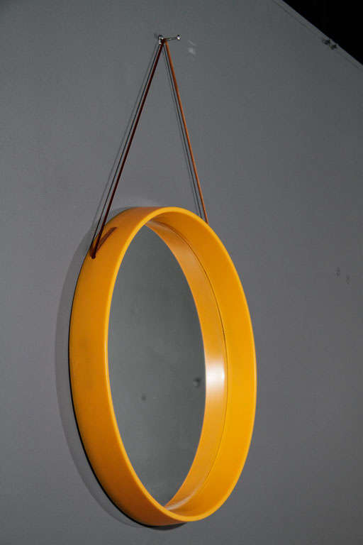 Resin mirror in yellow-orange with matching leather hanging cord.  Denmark, circa 1950.  Signed with foil label to back.

Measures 15.25 inches in diameter with 2 inch depth from wall.  Total height including cord is 24.5 inches.