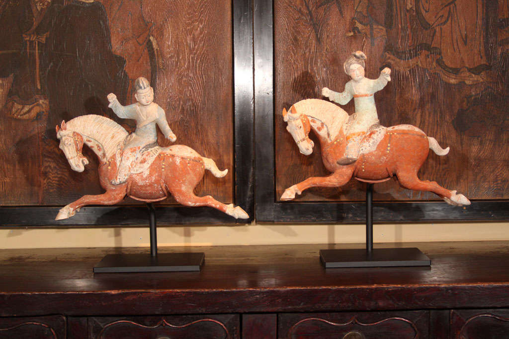 A pair of exceptional Chinese earthenware equestrian figures. Both horses in mid leap with a female and male rider each with arms extended. These are thought to represent players engaging in an equestrian sport similar to modern Polo. Each with