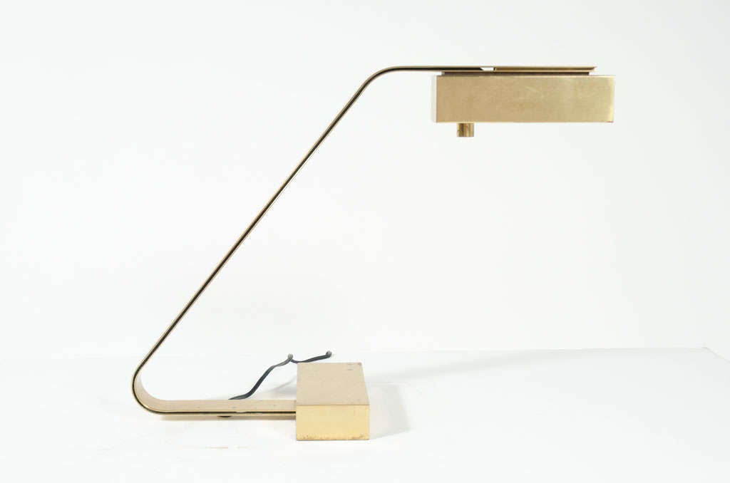 An austere desk lamp with integral dimmer in polished brass with a rectangular cantilevered shade that is attached to a double flat bar arm supported by a weighted rectangular base. By Casella Lighting. U.S.A., circa 1970.