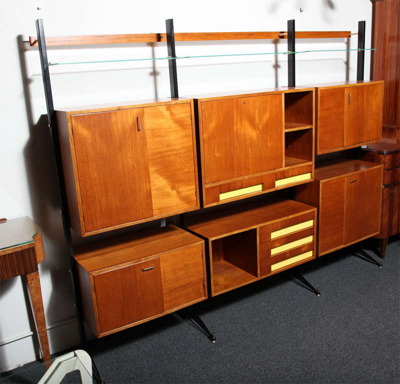 WONDERFUL MODERNIST 3 SECTION BOOKCASE MADE IN MILAN 1960 DESIGNED BY DASSI.WALNUT WITH 4 DRAWERS HAVING A YELLOW BACKGROUND IRON LEGS WITH BRASS ADJUSTABLE FEET AND 3 GLASS SHELVES ON TOP UNUSUAL FORM ,GREAT SIZE.