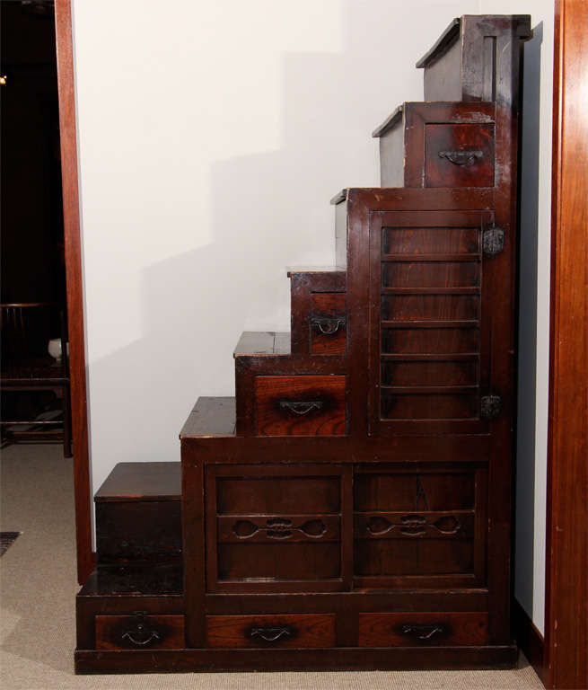 A fine Japanese Kaidan-dansu (staircase chest) rising to the right, the bottom two treads turned to the front. Constructed of Sugi (cryptomeria wood), the front facade with an asymmetrical arrangement of three drawers and hinged door (with sliding