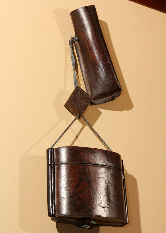 An unusual Japanese kanban (shop sign) from a tobacco accessory shop or inro maker. The sign in the form of an oversize tonkotsu (smoking set) consisting of a single-section inro (seal case), of lacquered wood, with stitched leather pipe case