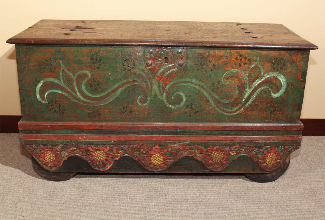 A fine wheeled rice storage chest (grobog) from East Java, Indonesia. Constructed of solid teak, the surface with polychrome decoration on a green ground. The skirt finely carved with traditional lotus blossom motif. With original iron hardware.