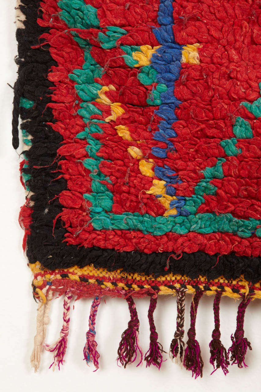 Los tejidos azilal se cuentan sin duda entre las alfombras bereberes más abstractas. Este ejemplo representa un par de árboles estilizados que flanquean un elemento central oscuro, posiblemente una cueva. Las alfombras Azilal de colores, como esta