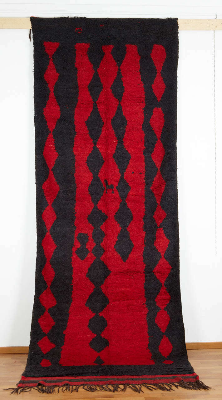 The Berber carpets of the Rehamna plain around Marrakesh are often distinguished by their minimalist character. This stunning example is conceived around two colours (blue and red), working in reverse for border and field. The asymmetry of the