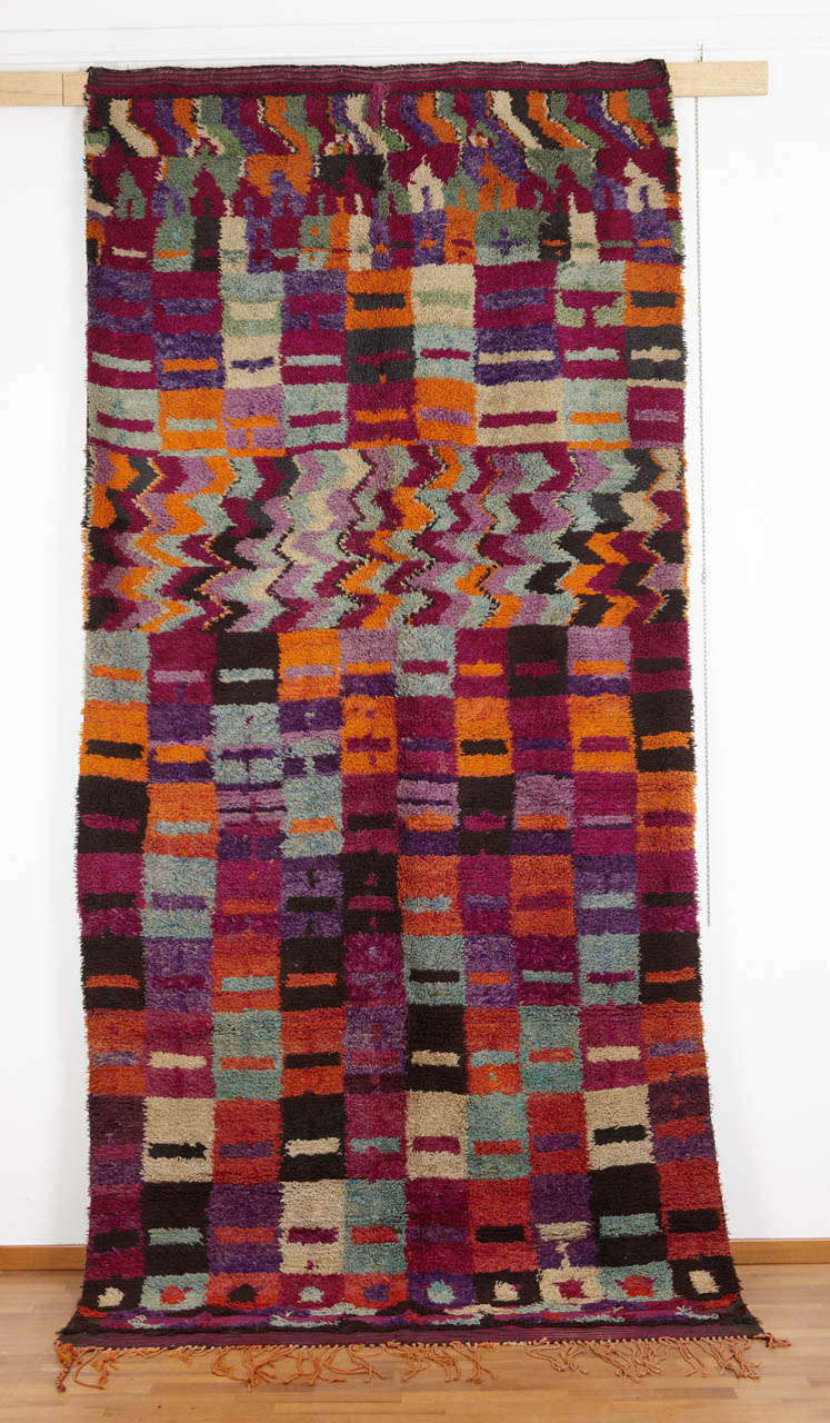 The Berber carpets from eastern Morocco, near the border with Algeria, are distinguished by wild patterns and audacious color combinations. This example displays all of these characteristics, the boldly colored chequerboard pattern being interrupted