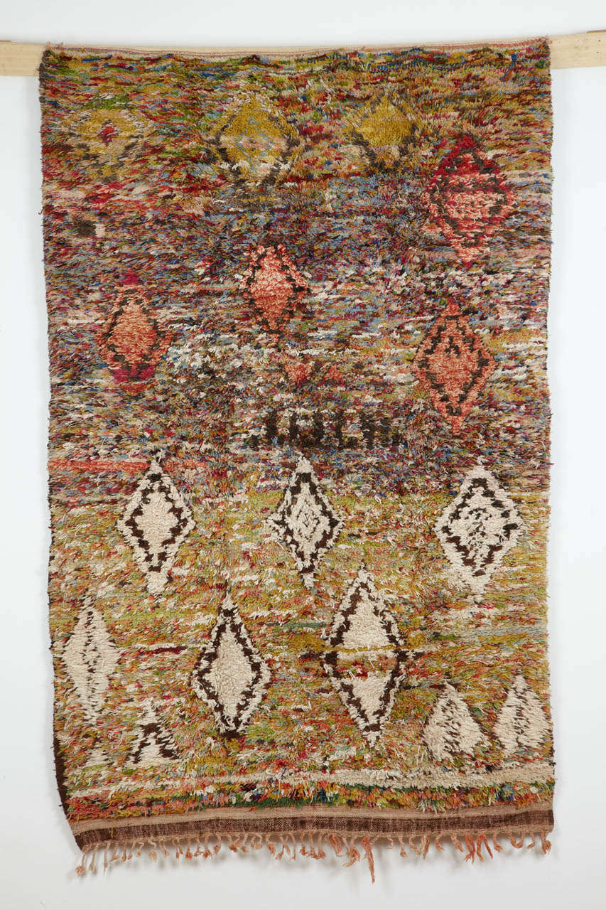 The rugs of the Beni Ouarain confederation of Berber tribes are typically recognised by their ivory background, with the pattern being embellished in the tones of brown or black. 
This rare example has a predominantly green background (with traces