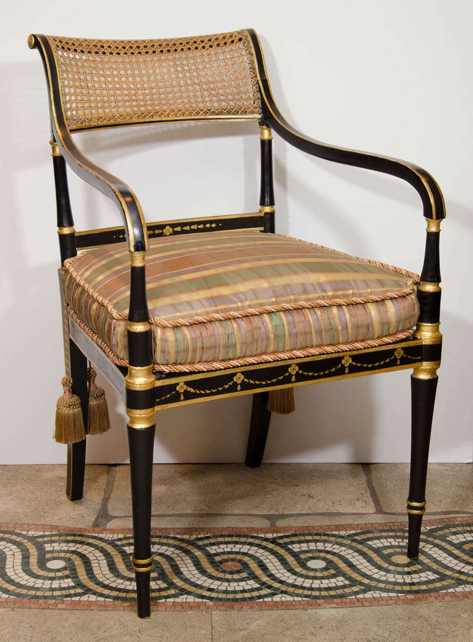 A good set of six Regency black lacquered and gilt stenciled caned open armchairs with loose cushion seats. Will separate into pairs.