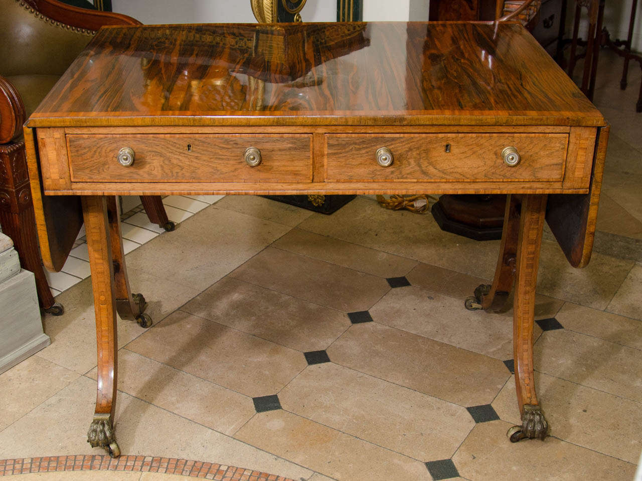 A fine Regency Rosewood brass banded drop leaf sofa table with trestle end supports on brass paw foot casters.
