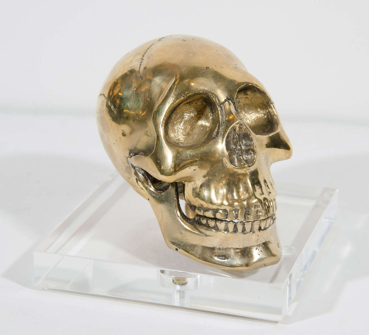 Large hand-forged brass skull bookend with square beveled Lucite base.
