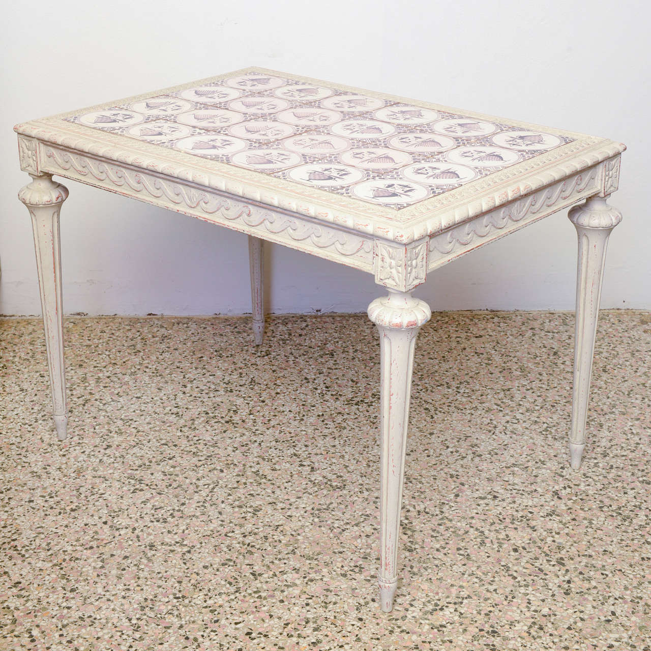 19th Century Swedish antique table with beautiful individual inset ceramic tiles; exquisite carvings surround the edge of table top, which sits on graceful tapered and fluted legs. Painted in whitish-gray distressed paint finish.

Circa Late 19th