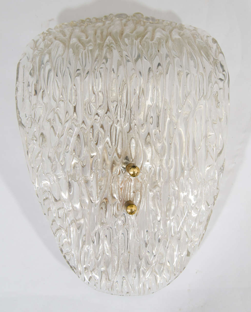 A clear translucent textured art glass wall sconce with brass hardware, Scandinavian Modern/Midcentury Modern period, by Carl Fagerlund for Orrefors, circa mid-20th century, Sweden. No chips noted. 
