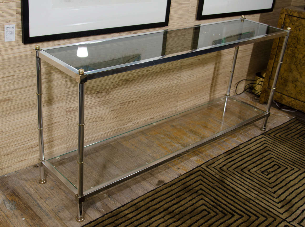 A vintage steel, brass, and clear and smoked glass two-tier console table inspired by Maison Jansen. 

Good vintage condition with age appropriate patina and wear. Some scratches.
