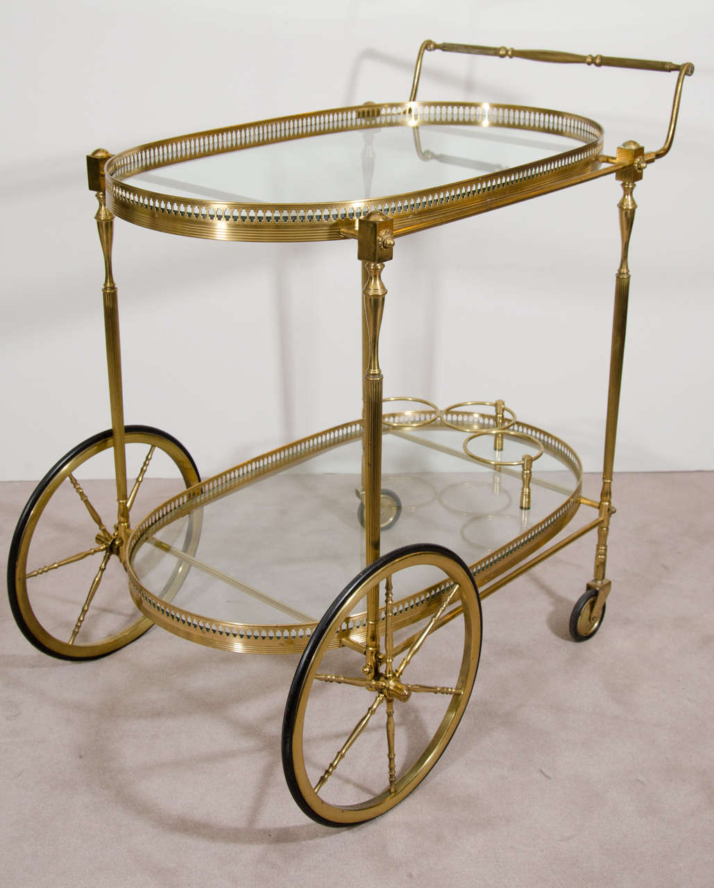 A vintage 1960s brass and glass bar cart with faux bamboo accents. There is a galleried top, two glass shelves, and three wine holders. 

Good vintage condition with age appropriate wear. There are a few minor chips in the glass on the top shelf
