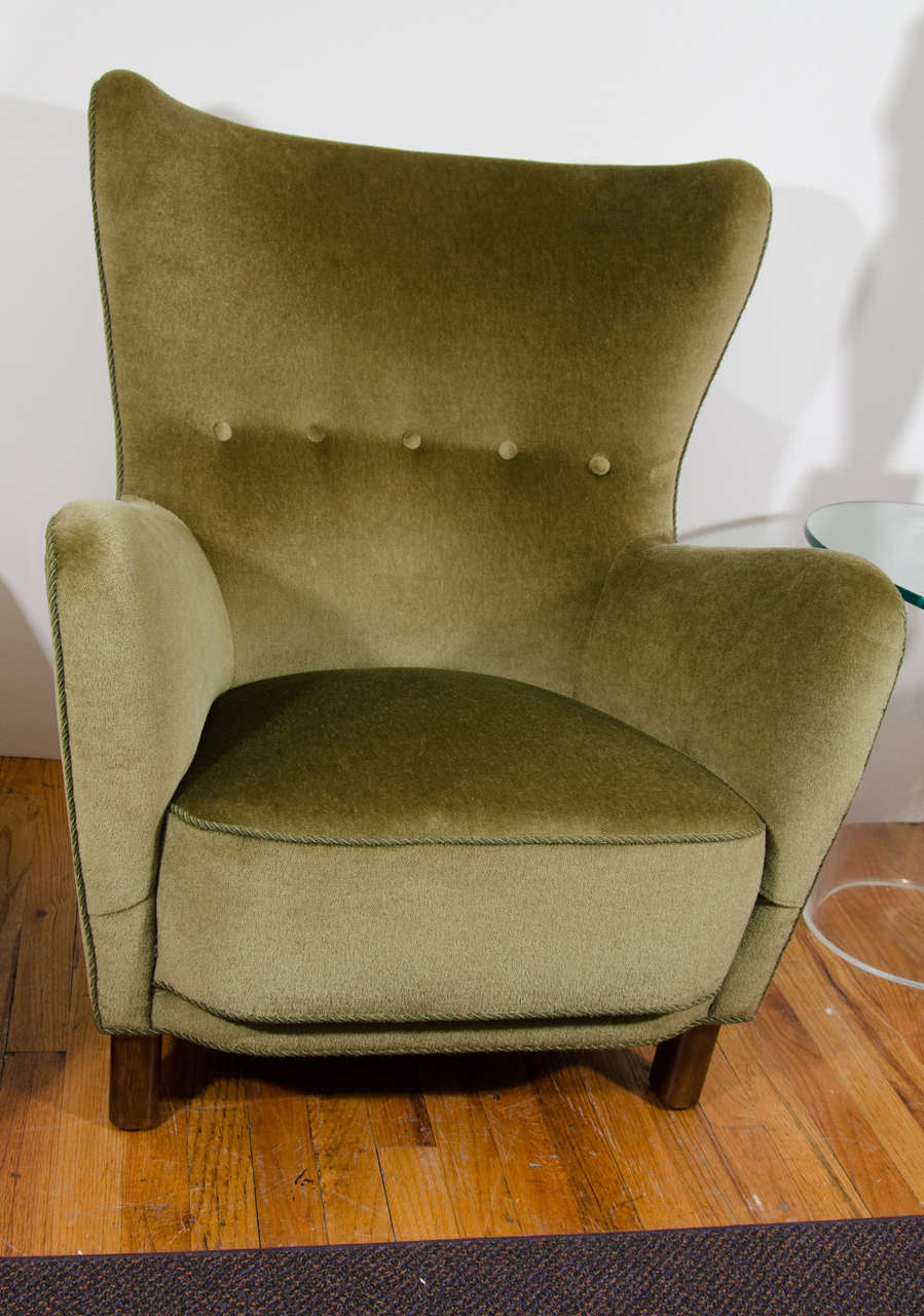 A vintage Fritz Hansen high back lounge chair or wingback armchair with button tufted plush olive-green upholstery.