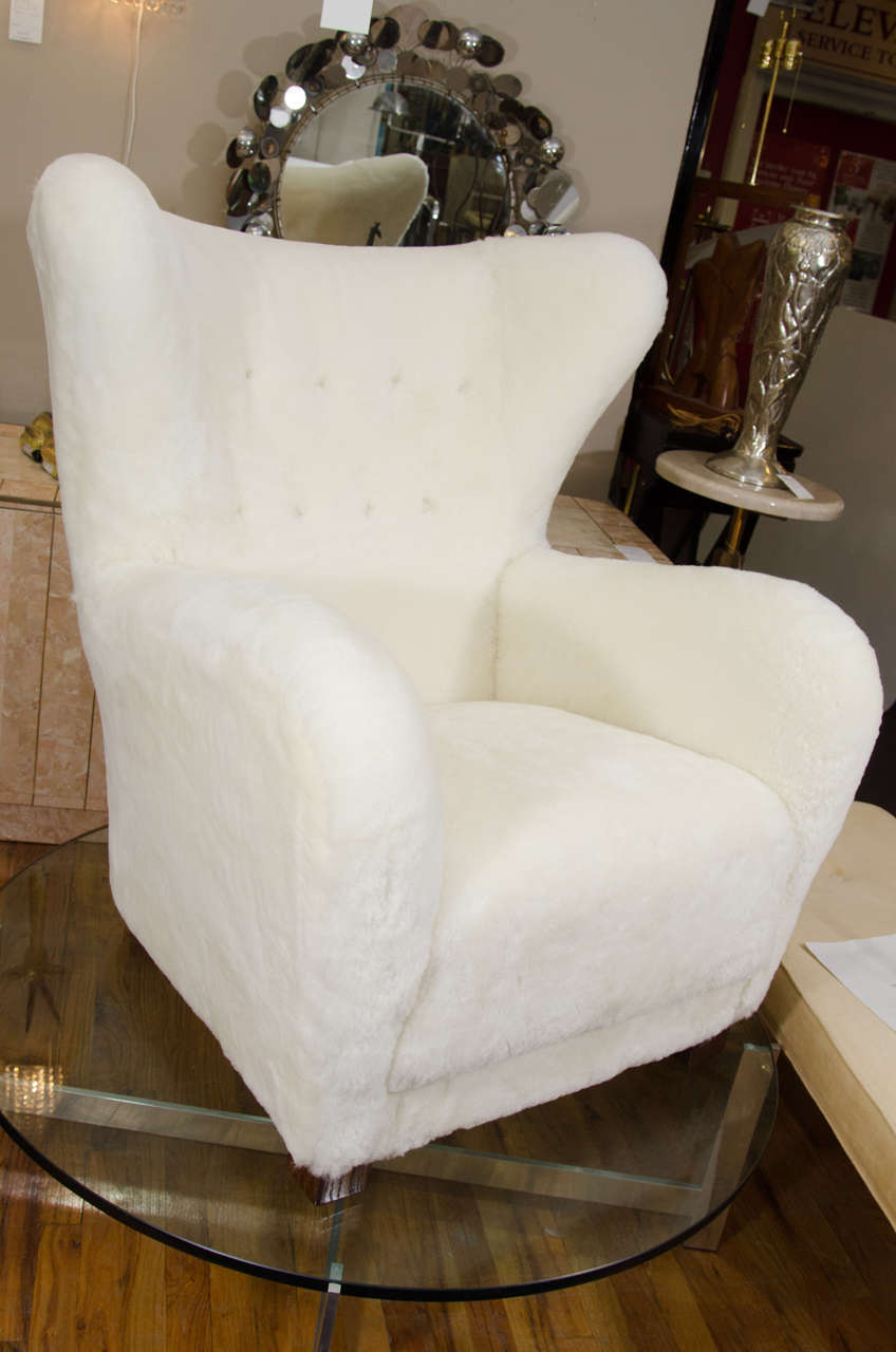 A circa 1950s Danish modern lounge armchair, in the style of Flemming Lassen. With extravagant wingback, upholstered in sheepskin, with button detail on the backrest. Excellent vintage condition, with no visible wear; newly reupholstered in
