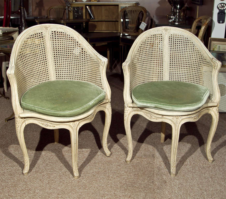 Pair of exquisite painted French Louis XV style corner chairs, circa 1940, each with caned back and green velvet cushions, raised on cabriole legs. By Maison Jansen.