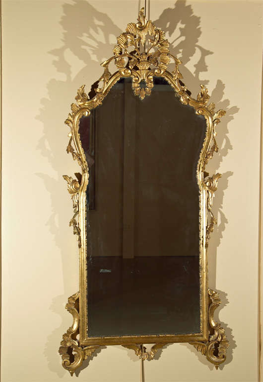 Italian Rococo style giltwood mirror with intricately carved scroll and foliate frame.