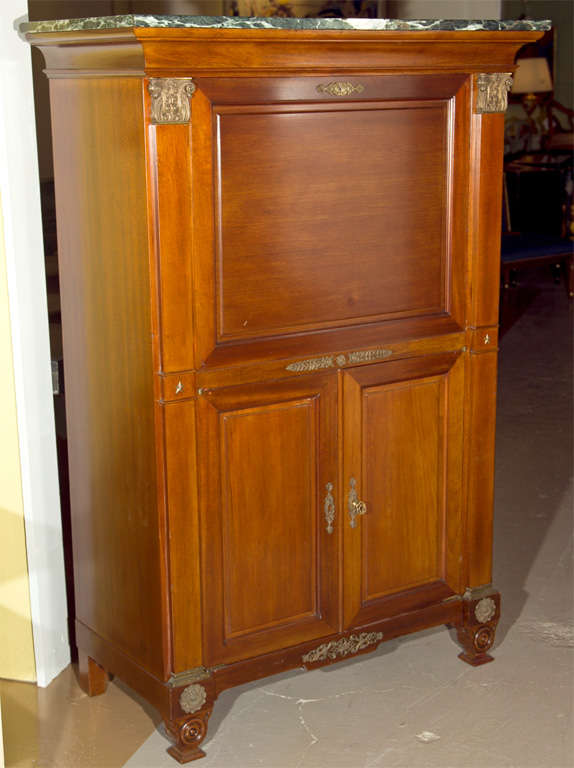 French Empire style mahogany bar, circa 1940s; the green marble atop a conforming case with a drop front opens to a glass interior, over a two-door cabinet. 