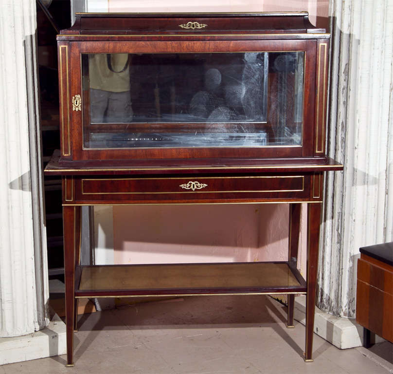 A fine French mahogany and bronze banded liquor cabinet or bar, circa 1940s, the enclosed top with glass door and mirrored interior, above a stand with a frieze fitted with a single drawer, supported by tapering squared legs joint by a lower tier