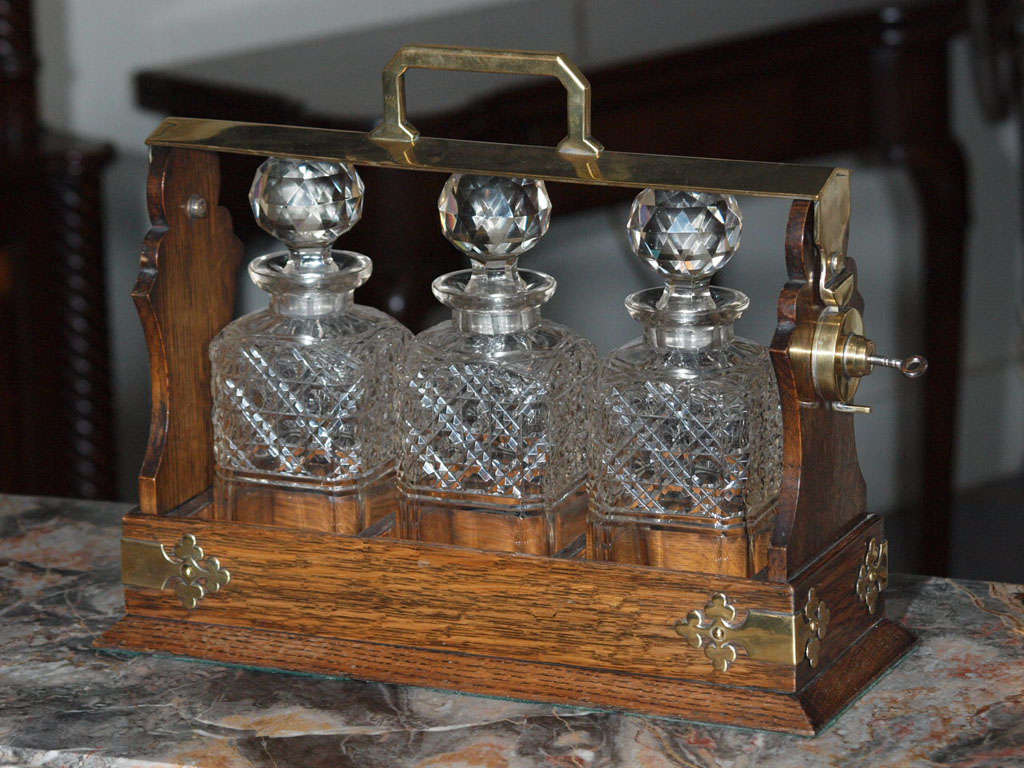 (L-5550) Antique English oak & brass three-bottle tantalus set.