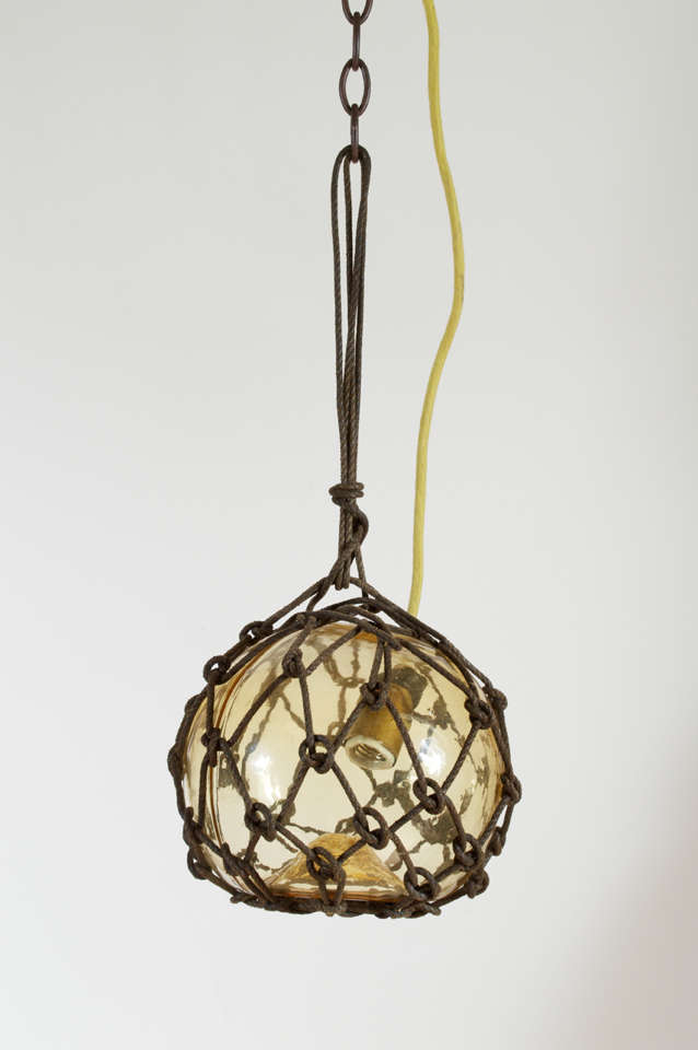 Japanese fishing float made into a pendant light. Simple yet unique design, available in different colors (see other postings). This pendant is a pale amber, a light gold glass color. These have been newly wired and are in great condition.