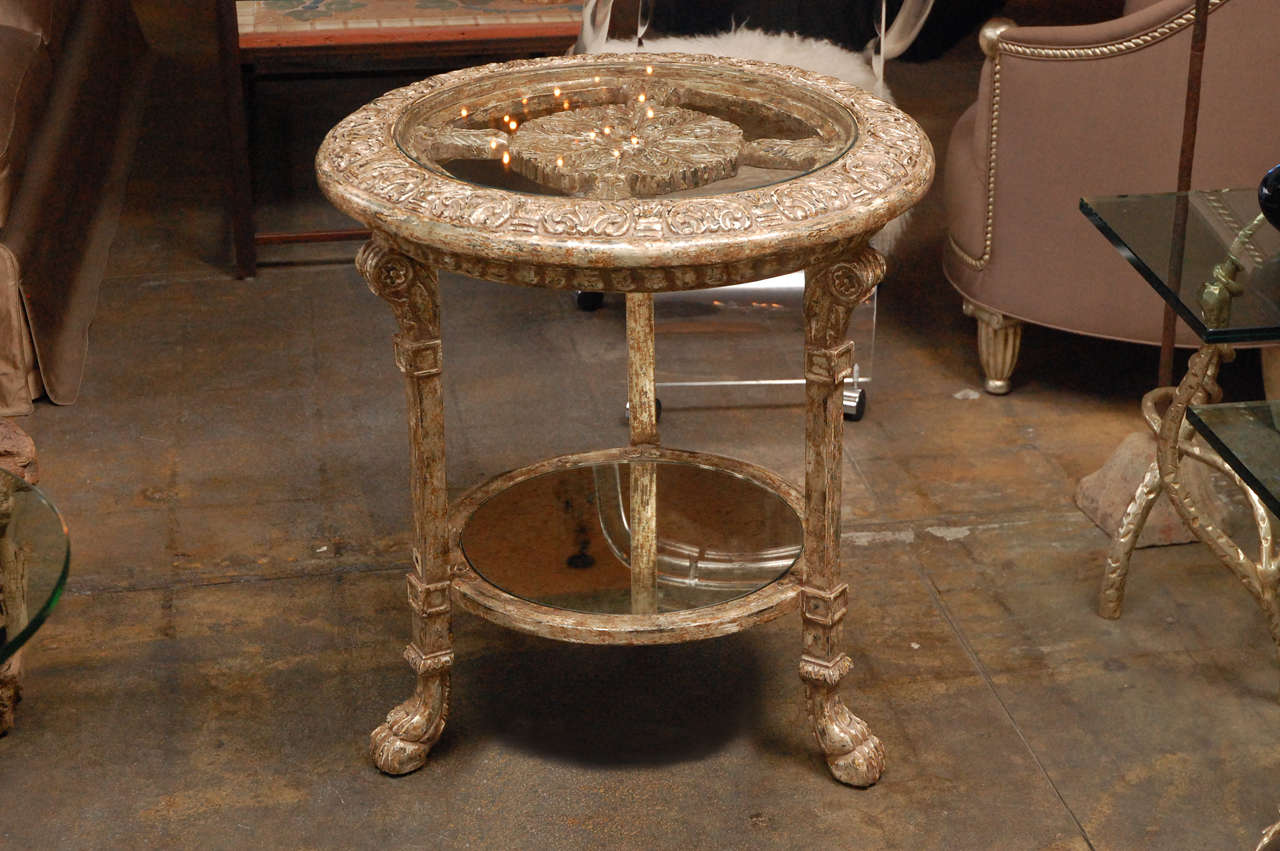 Heavily carved and gilded (12-karat white gold) two-tiered table with glass top on top tier and antique mirror on bottom tier.