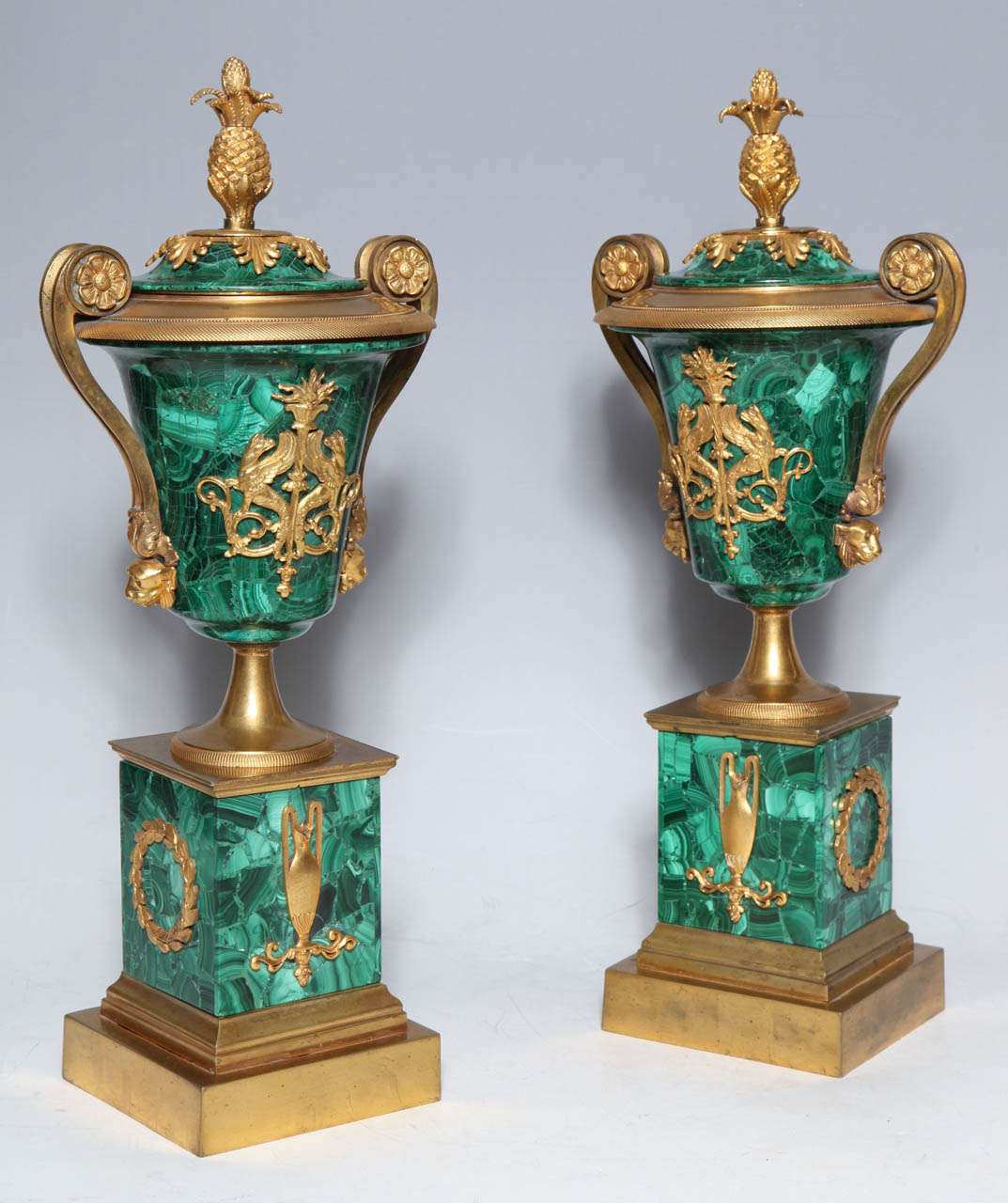 A very fine pair of Antique Russian Empire period, Ormolu mounted and Malechite covered vases. Each vase having a pair of handles starting with rosettes and tapering down, resting on a pair of lions heads, covers adorned with a pair of fine Empire