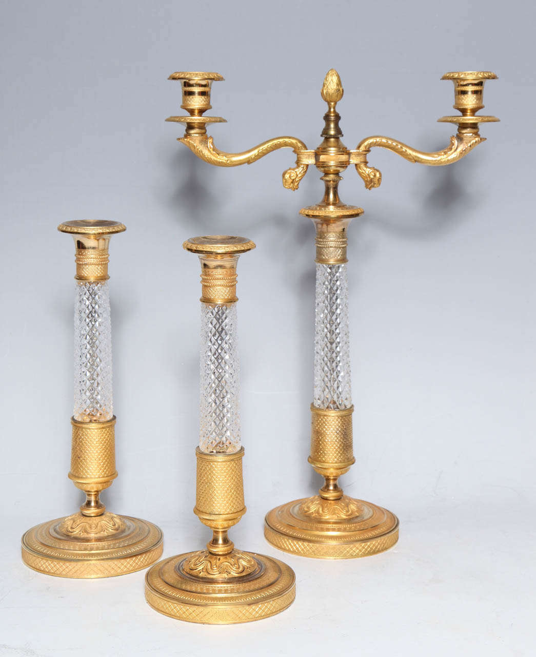 A very fine three-piece garniture of antique French hand diamond cut crystal and doré bronze-mounted candlesticks.