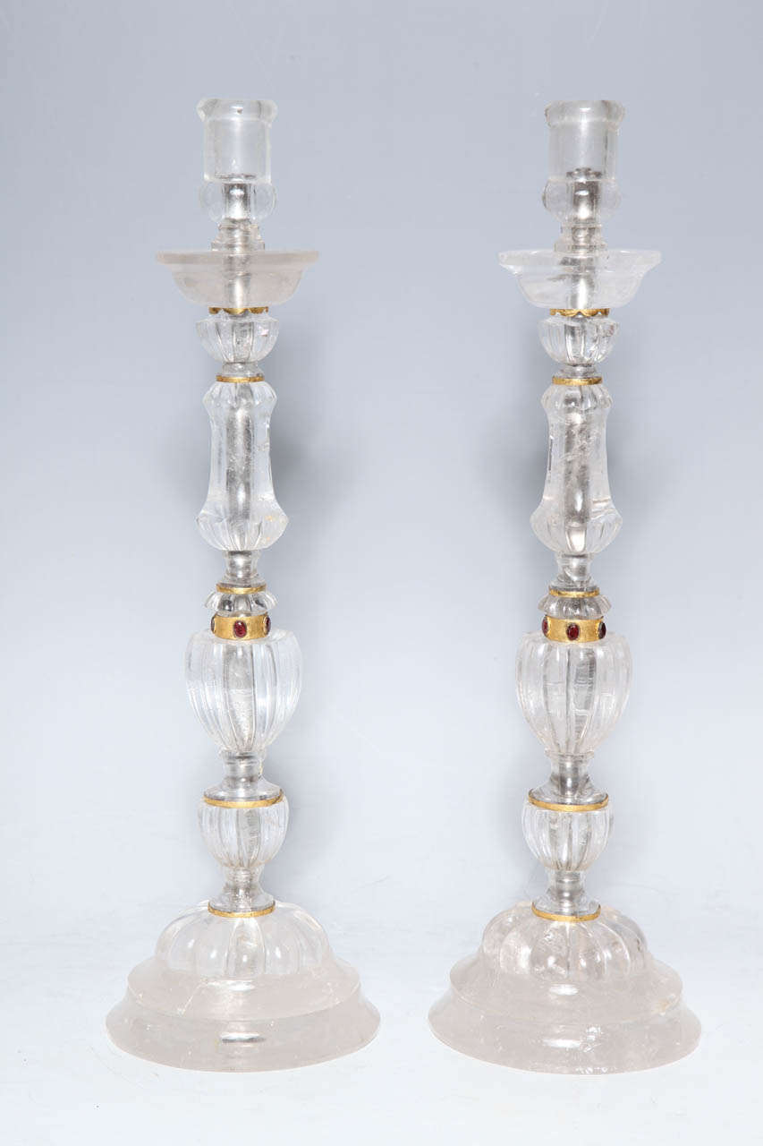 A Pair of Massive Hand Carved Jeweled Rock Crystal Candlesticks,with Mercury Gilded Bronze Mounts.The Multi Shaped elements are adorned by 3 Carat Ruby Red Garnets on each side and blend into a harmonious whole. These sticks can be wired to form