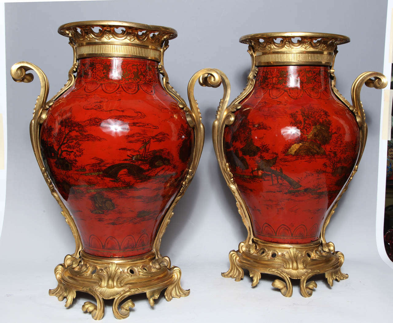 A large pair of antique French transitional period red lacquer, chinoiserie decorated ormolu-mounted vases with gilt bronze Rococo mounts. The vibrant color of these highly polished vases is enhanced by the beautiful scenes of mountains and rivers