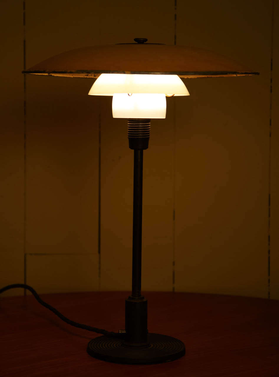 Designed for Louis Poulsen in 1933. Fluted brown-lacquered metal foot, and bakelite socket cover with through-switch, with 3½ yellow-painted metal top shade and middle and lower shade in opal glass.  Nice worn patina on the metal painted shade.