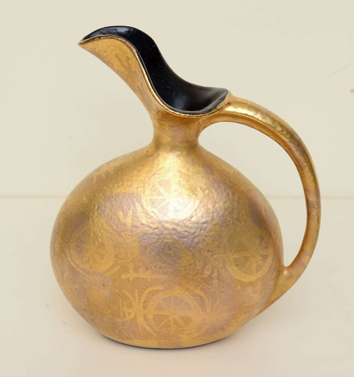 The applied and painted design over ceramic makes a rich looking ceramic vessel in pitcher form.
This is from a California potterist company and is very unusual for their work. it has a gold painted applied wheel design form over the fired ceramic