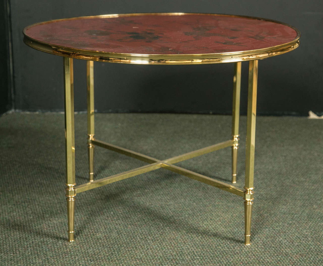 A post war French circular coffee table.   The table has a polished brass base and red lacquer chinoiserie top depicting a nature inspired scene with birds.