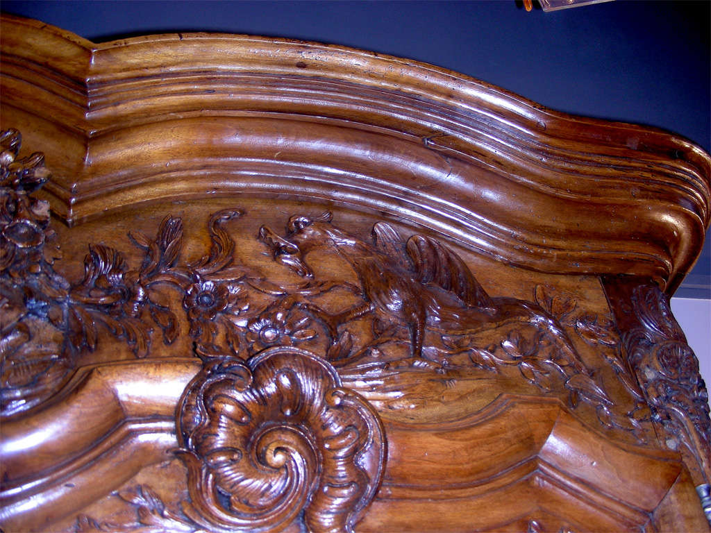 Handsome large 18th century period Régence armoire, in finely carved walnut, from the Lyons region in France, with the coat of arms of the Burgundy Dukes.  A young couple is at top center, surrounded by flower wreaths and flanked by Chinese-style