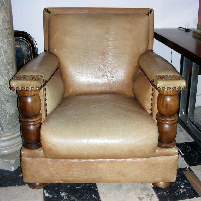 Two large 1940s armchairs in natural wood and leather upholstery with metal studs.