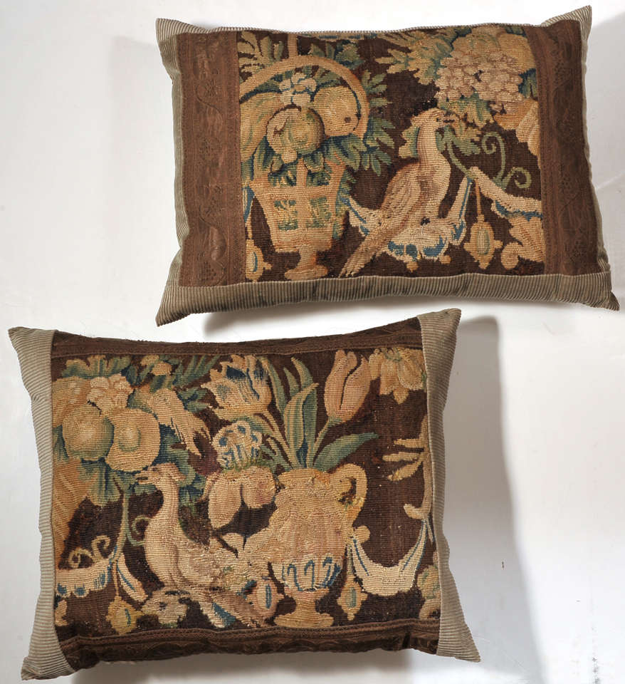 Pair of 18th century material tapestry pillows embellished with French gallon in a Classic pattern. Both tapestries depict birds. One is with a Classic urn with flowers and fruit. The other is with a basket of flowers and fruit. The pillows are