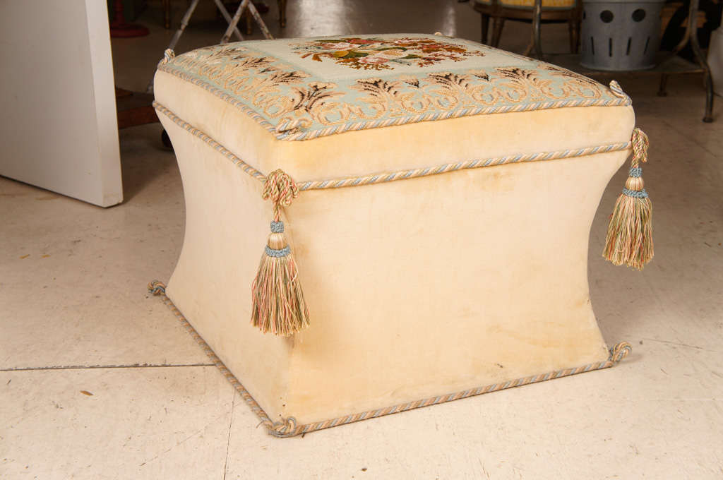 Victorian style needlework and upholstered ottoman. The square
floral needlework seat with foliate celadon-ground border and tassels at the corners on waisted velvet covered base.