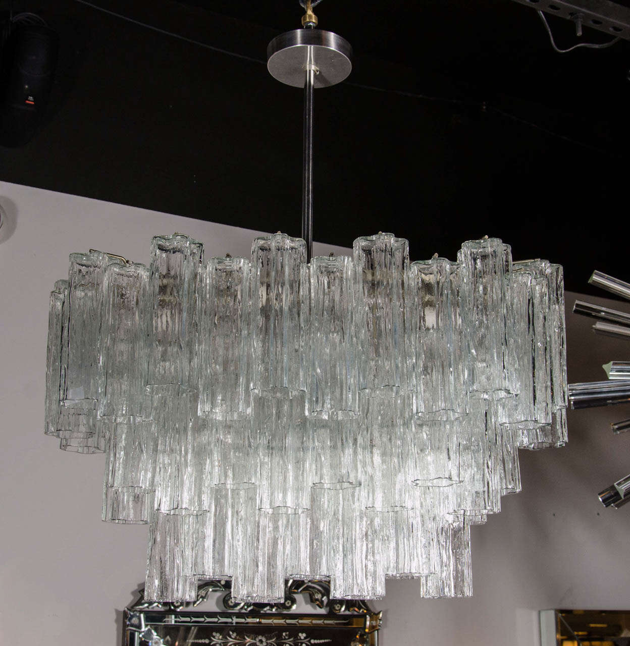 This gorgeous Mid-Century 'Tronchi' chandelier by Venini consists of numerous tubular Murano glass shades hung over three tiers at alternating heights giving a cascading effect. The tubular shades are textured and clear and look star shaped when