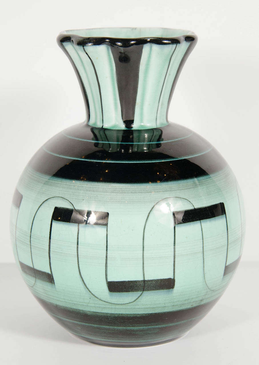 This exquisite vase by Ilse Claussen of Sweden has a round bulbous form and tapered top. In aqua blue green glaze with stylized hand painted black geometric Art Deco detailing.  Signed on the bottom with Ilse Claussens initials as well as the