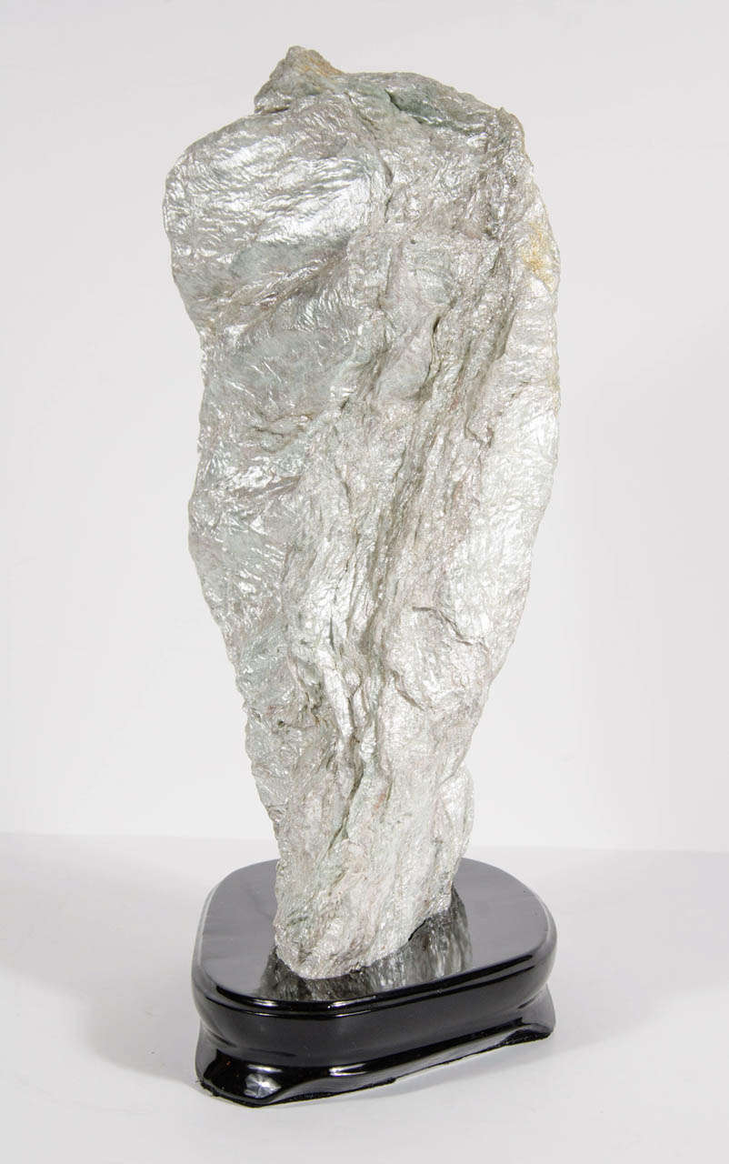 A very rare and unique mineral specimen in soft shades of sage and oyster with an iridescent pearl finish.  It is mounted on a ebonized walnut pedestal base. This compelling natural object would make a beautiful addition to any decor.