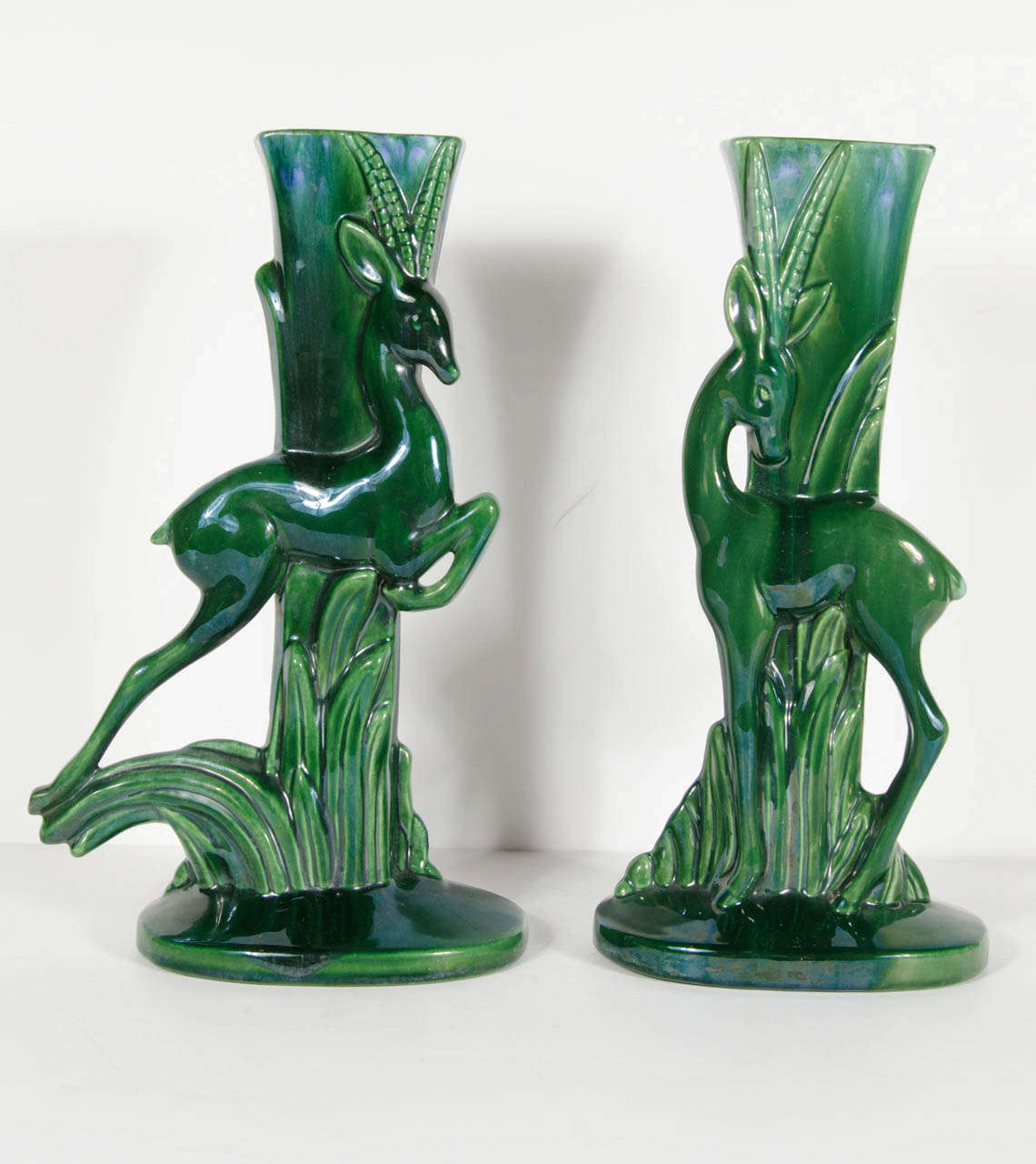 This gorgeous pair of hunter green glazed ceramic vases feature a gazelle with stylized Art Deco foliage and fauna.