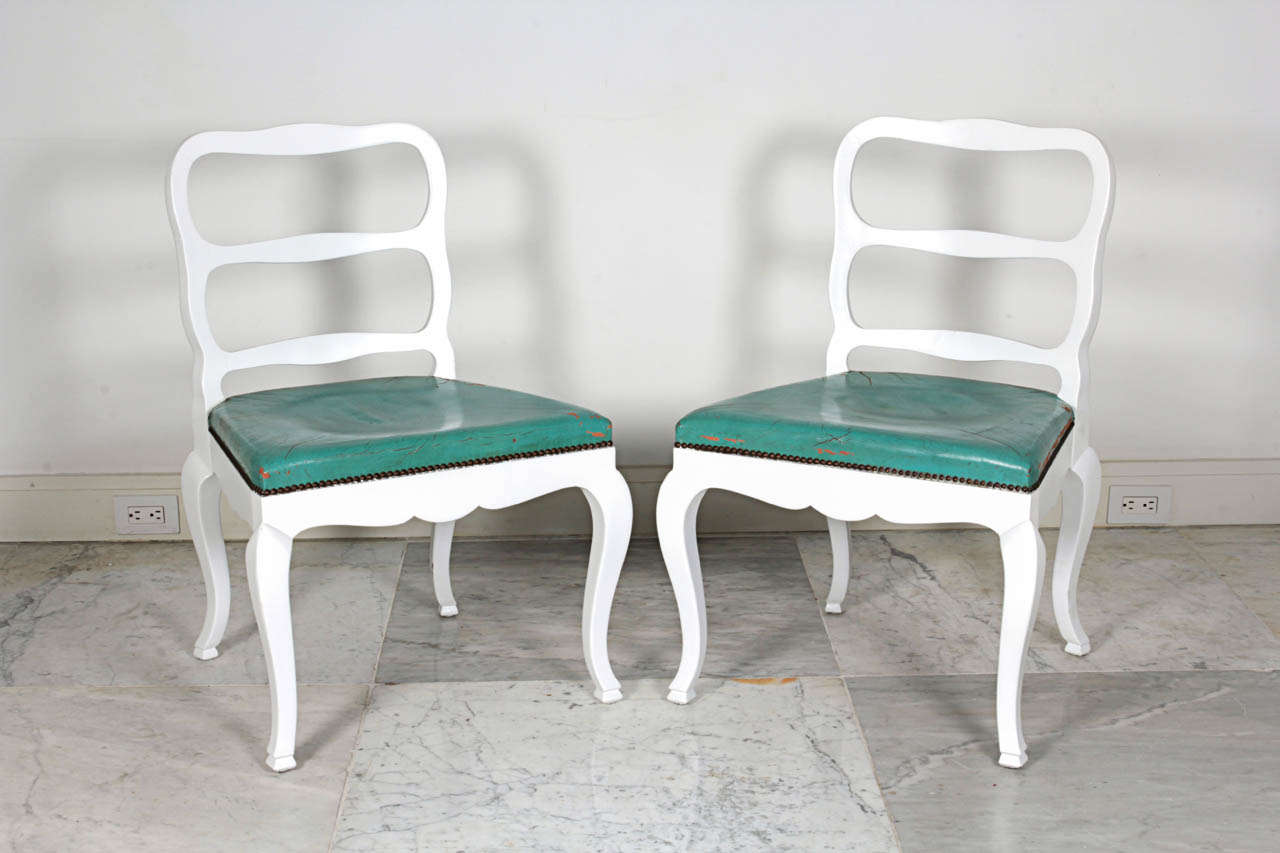 Pair of white painted slipper chairs with turquoise leather seats.
