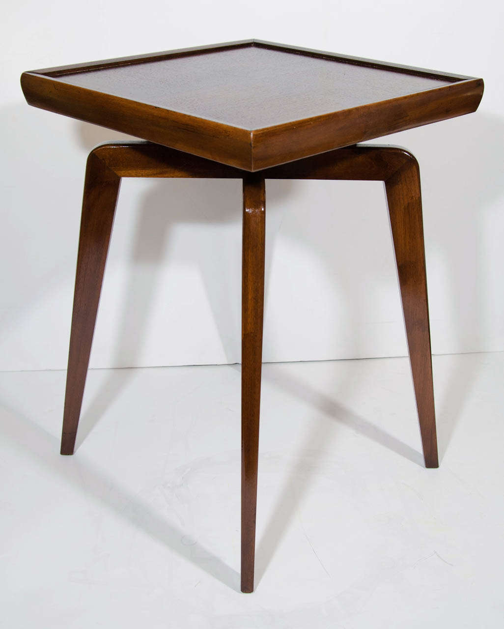 Pair of modernist side tables with streamline square tops and sleek criss-cross pedestal bases with spider leg design. The tables are made of walnut wood and have wood panel inset tops with the grains running in opposing directions, creating a