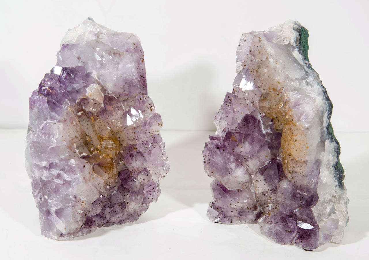 Pair of extraordinary bookends with rough and large chunks of crystaline quartz and amethyst crystals throughout in varying hues of violet.  The bookends also features rare and unique details of citrine crystals along the center, creating the muted