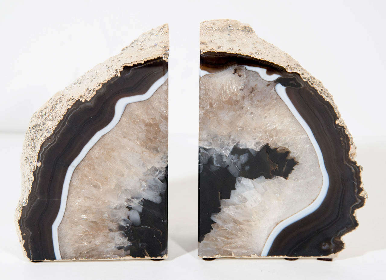 Pair of natural agate stone bookends with hand cut and polished crystaline centers. The bookends have rough exterior edges and backsides that have been beautifully plated by hand in 24k Gold. The agate has beautiful hues of onyx, buff, and taupe,