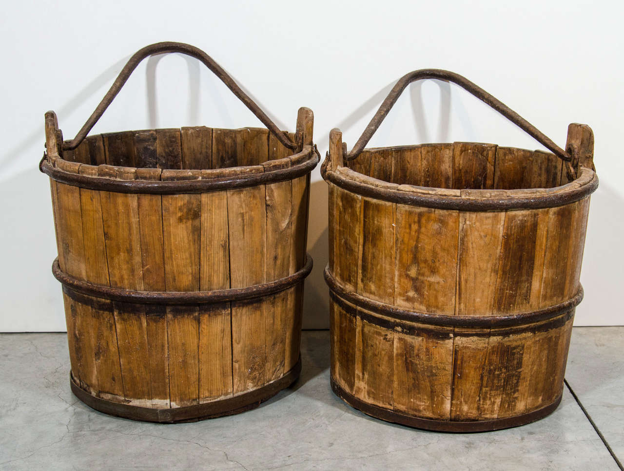 Two Chinese cypress water buckets with striking cast iron handles and straps.Nicely worn.  Priced individually.
From Shandong Province, c. 1920. 
BT377