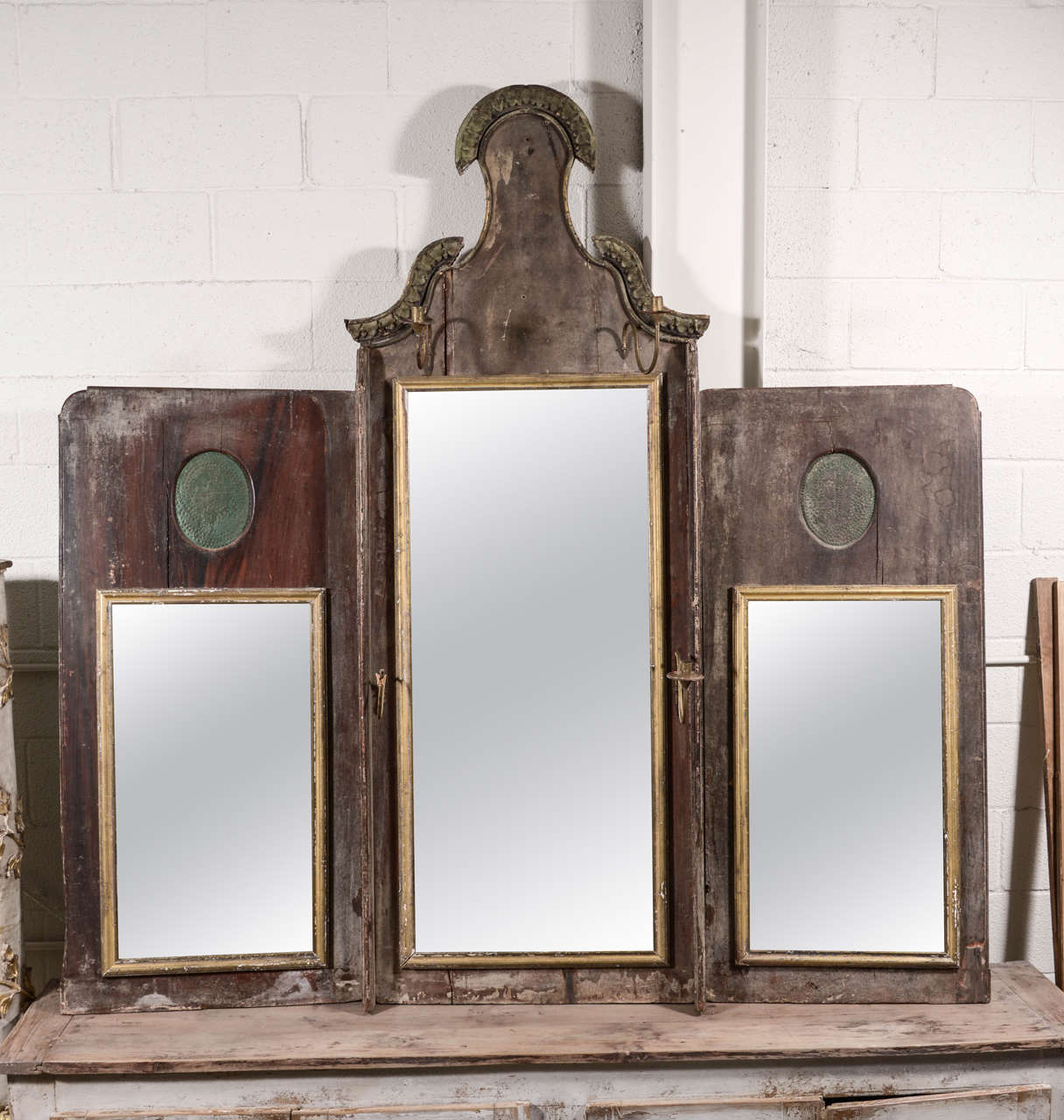 This handsome Italian Triptych mirror is complete with its original mercury glass. Features wood carvings attached on top and four metal, removable sconces. This piece is of the neoclassical era and holds true to the Vitruvian principles of that